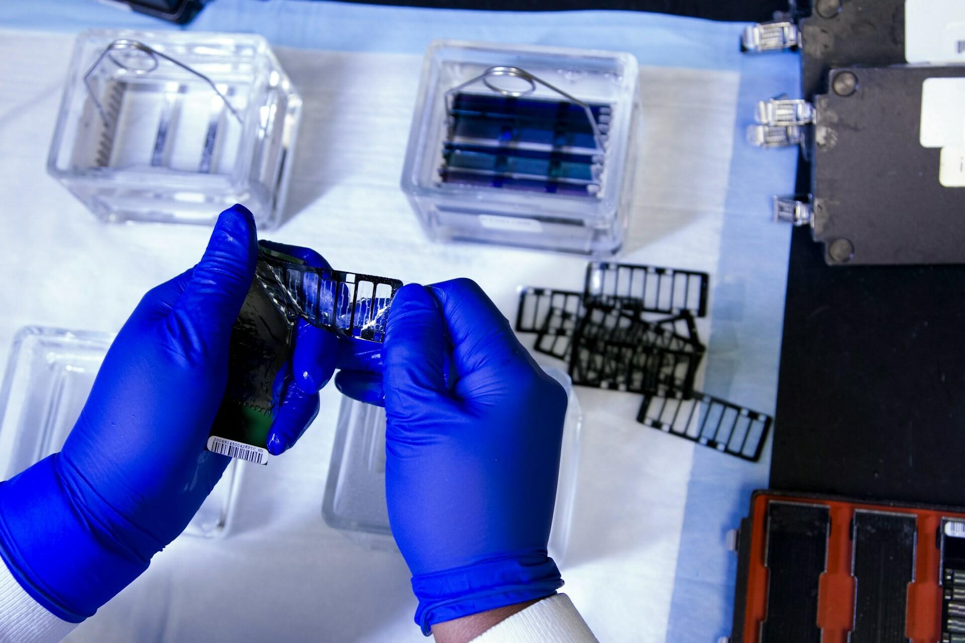 Arbeit im Labor Hände in blauen Handschuhen lösen den Barcode an einem Objekt ab