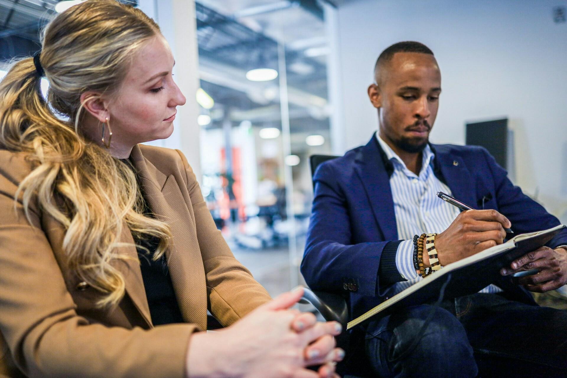 Meeting Eine Frau blickt auf die Notizen ihres Kollegen im Business-Meeting
