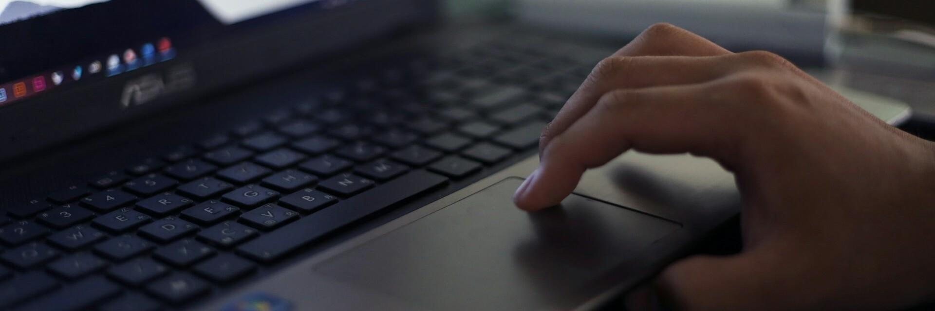 Hand auf Laptop Finger einer Hand befinden sich auf dem Touch-Display eines Laptops