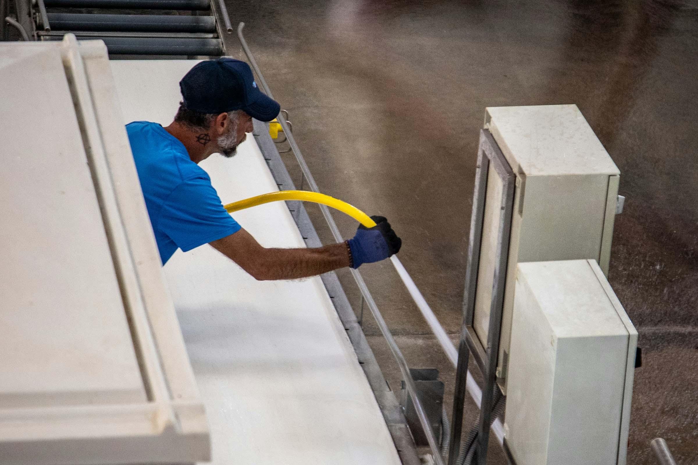 Reinigung Person reinigt ein industrielles Förderband mit einem Schlauch