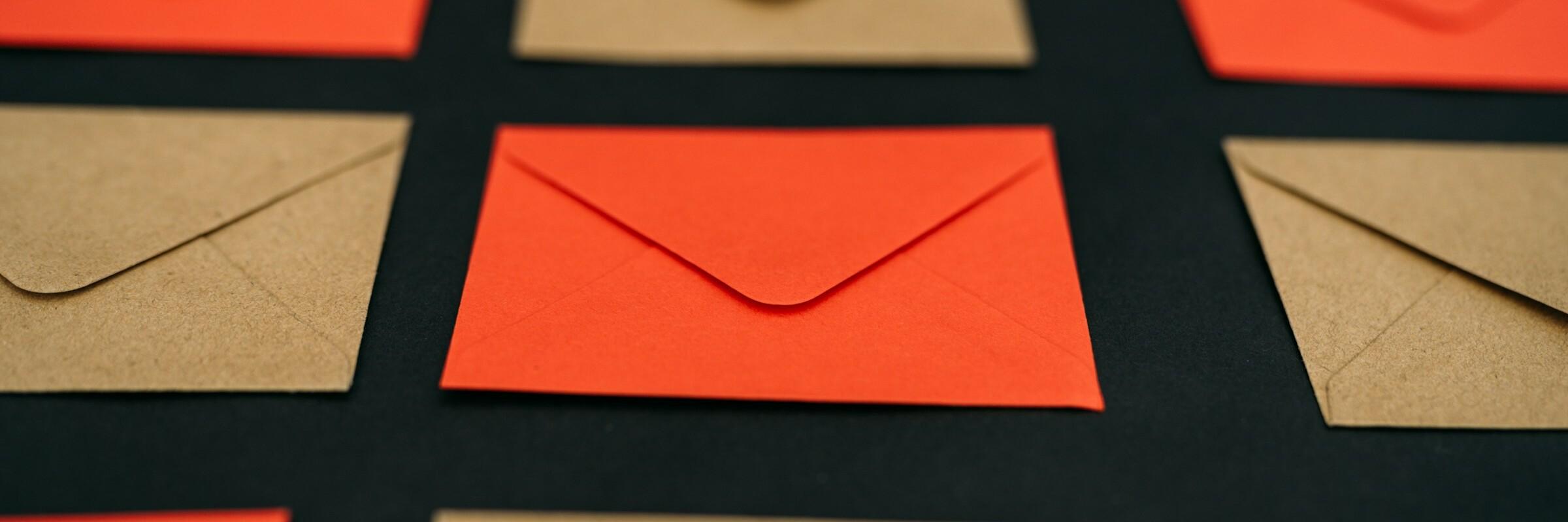 Braune und rote Briefumschläge liegen im Wechsel nebeneinander
