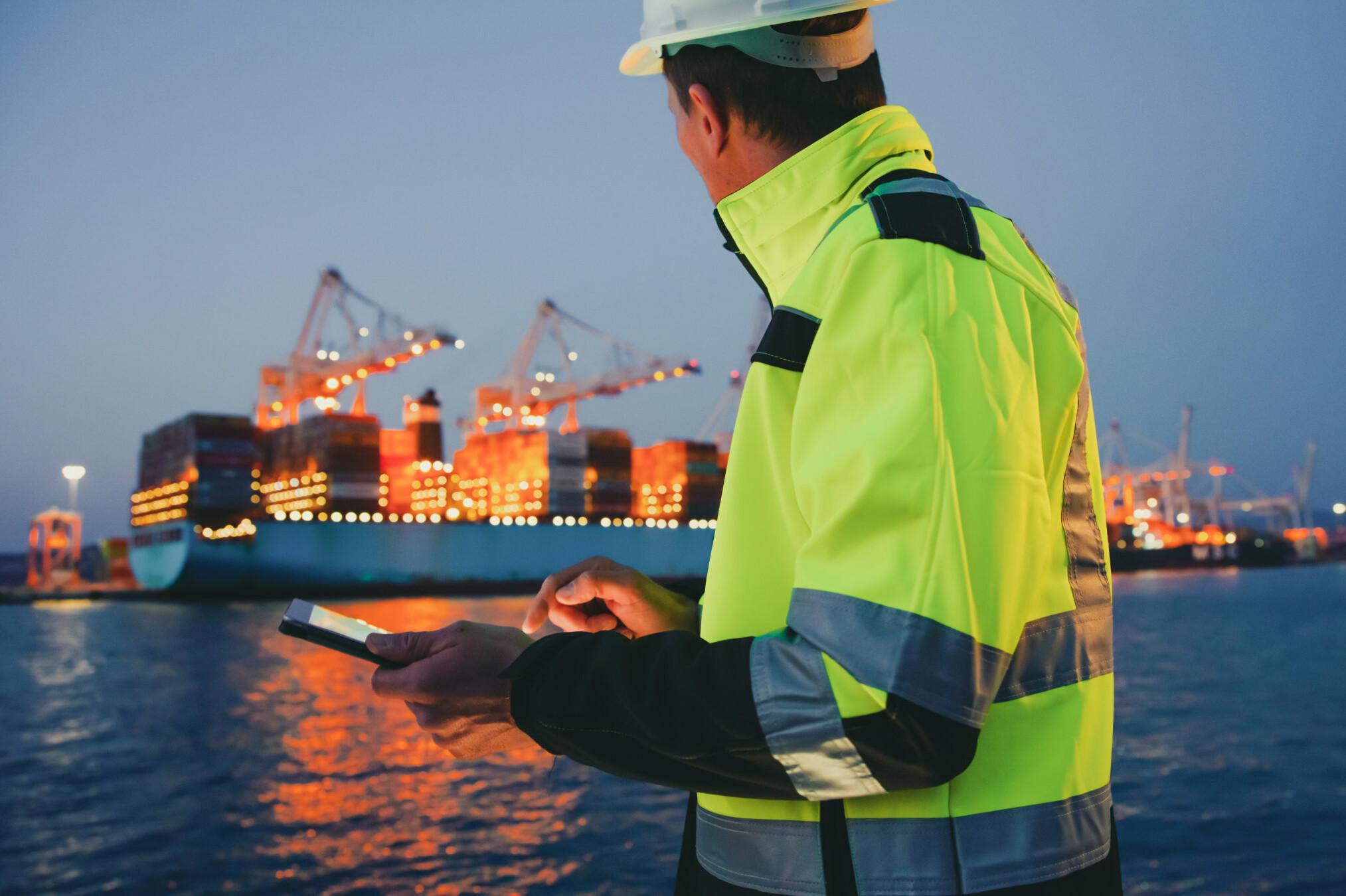 Hafenarbeiter Dock worker with tablet watches a ship being loaded