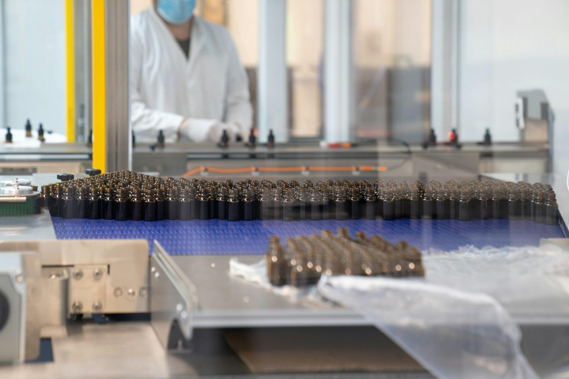 Förderband Fabrik There are several vials of medicine on a conveyor belt in a factory.