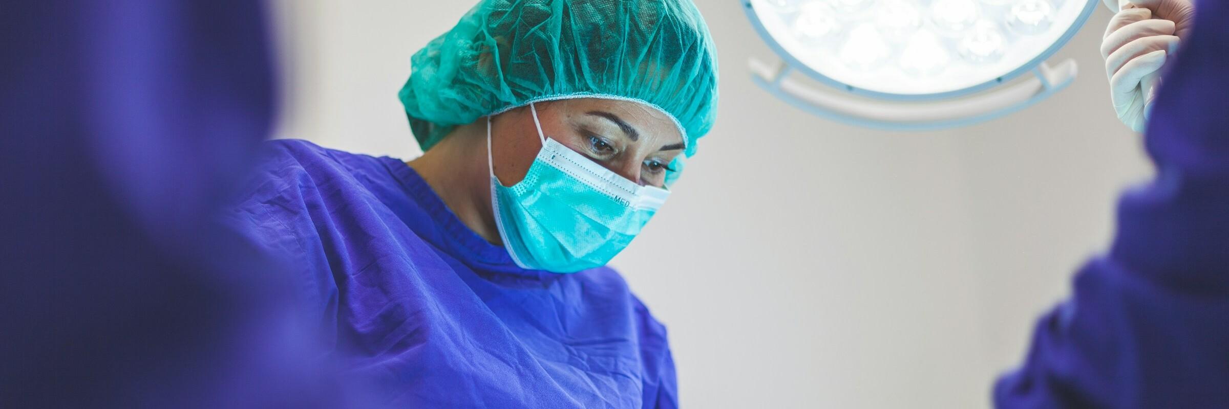 Operation Frau mit blauem Kittel und Mundschutz operiert