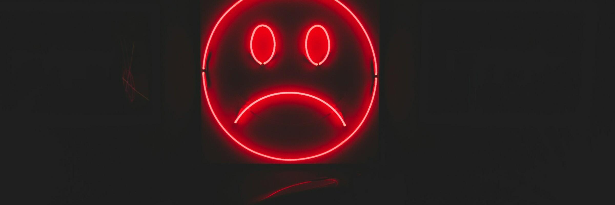 Trauriges Emoji Rotes trauriges Emoji vor dunklem Hintergrund