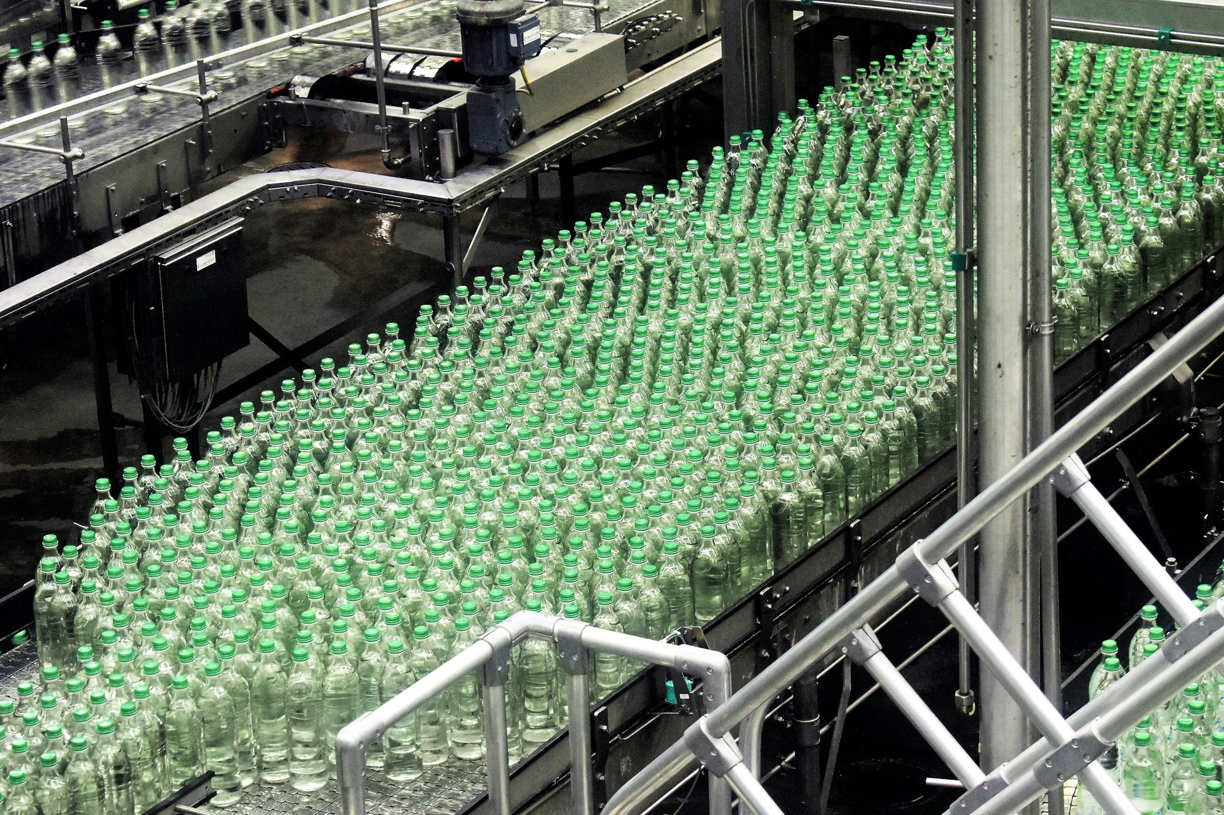 Verpackungslinie in Produktionshalle Flaschen mit grünem Verschluss in einer Verpackungslinie in einer Produktionshalle