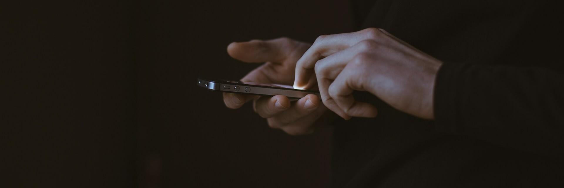 Handy im Dunkeln Hände halten ein Handy in der Hand