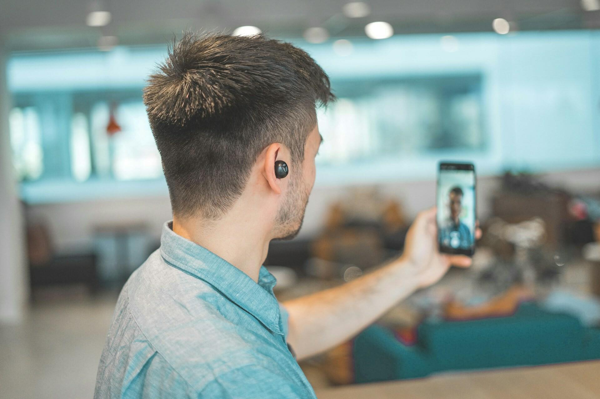 Video-Call Mann mit Knopf im Ohr führt einen Videocall auf seinem Handy