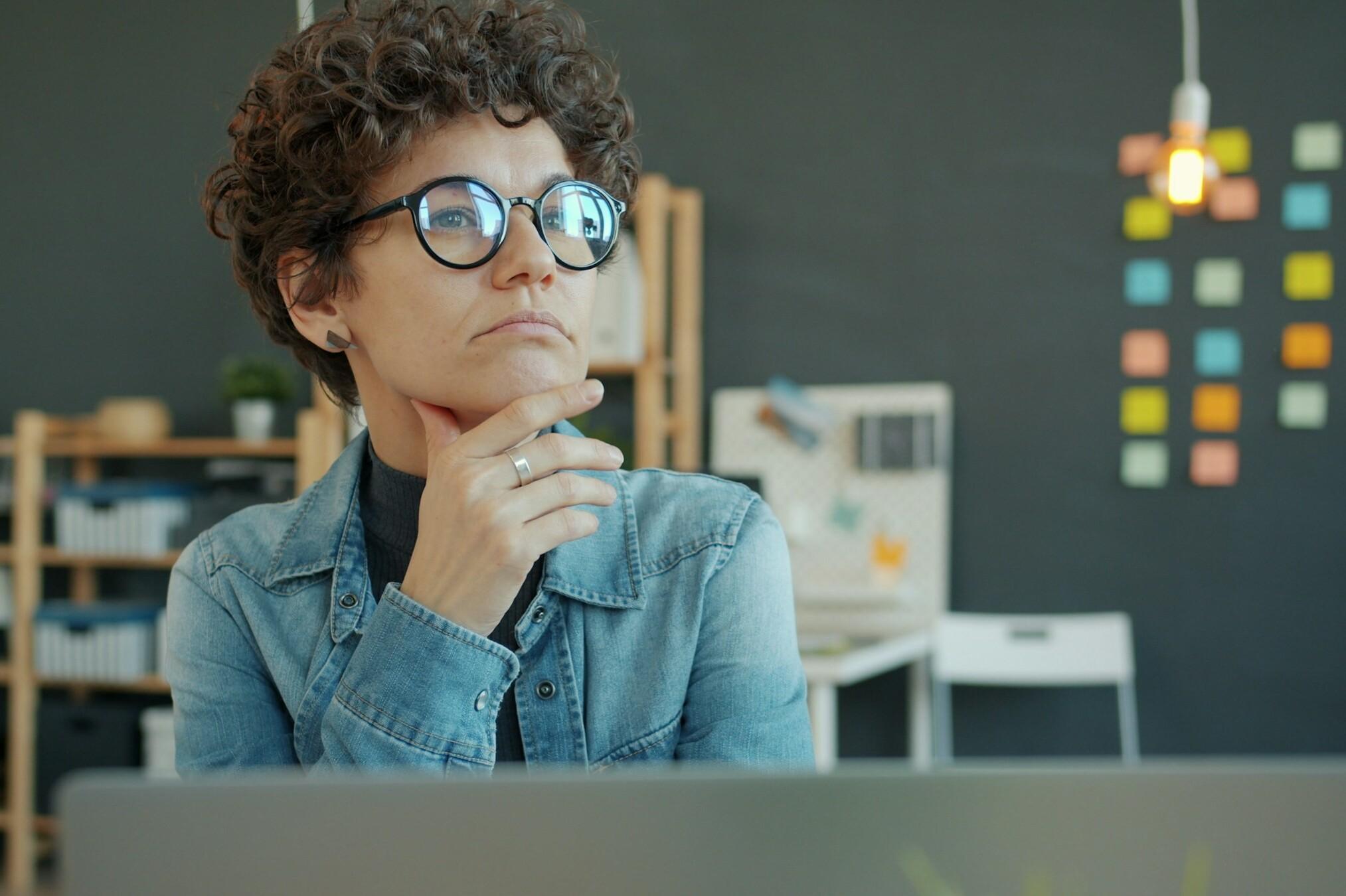 Frau im Büro Eine Frau sitzt am Schreibtisch und denkt nach