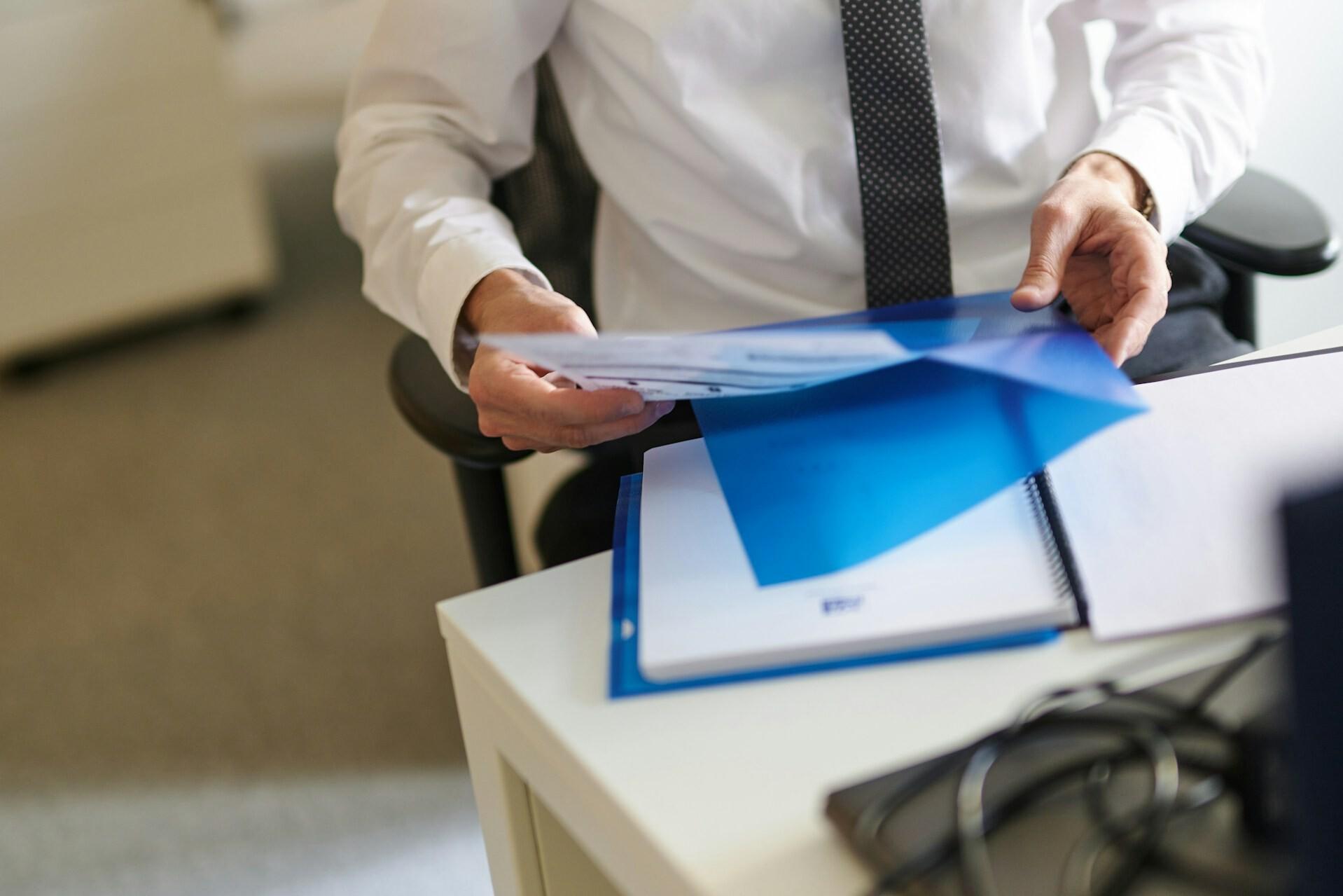 Dokumente sortieren A man places a sheet of paper in a clear blue sleeve