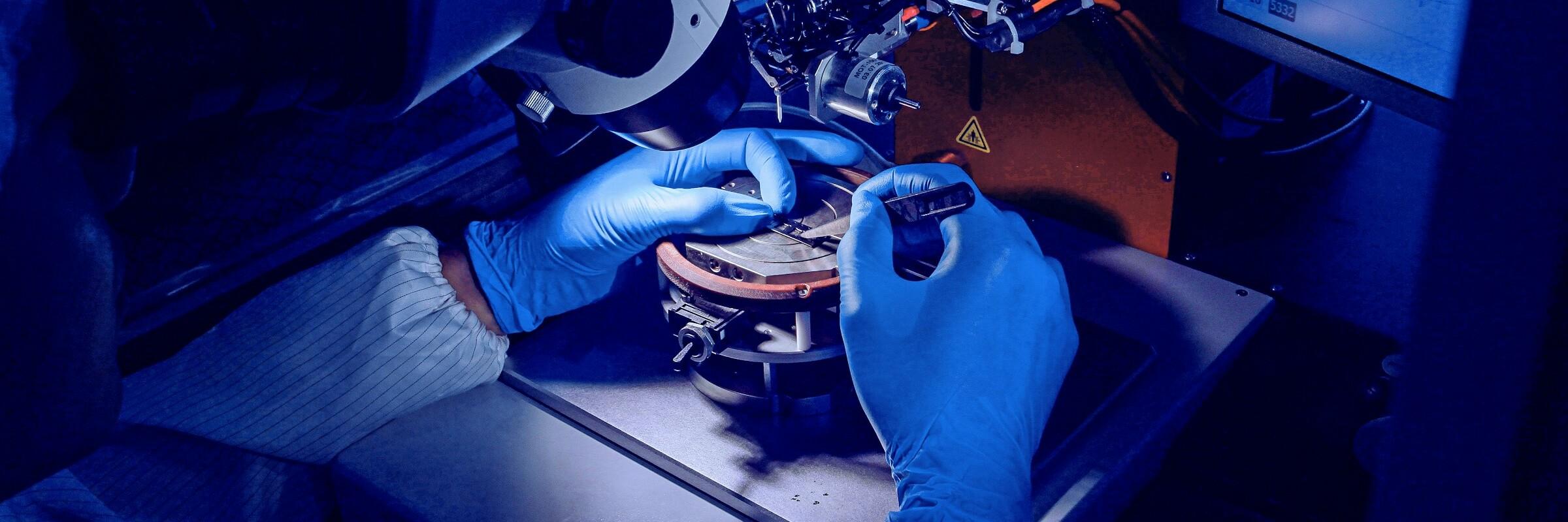 Maschine Präzisionsarbeit von Händen in blauen Handschuhen an einer Maschine