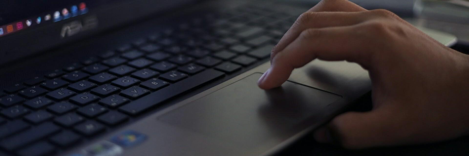 Hand auf Laptop Hand auf Laptop-Tastatur