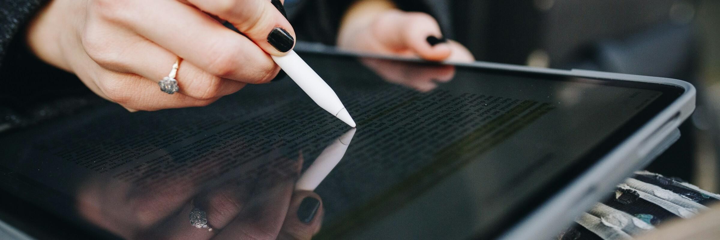 Hand einer Frau prüft einen digitalen Vertrag auf einem Tablet